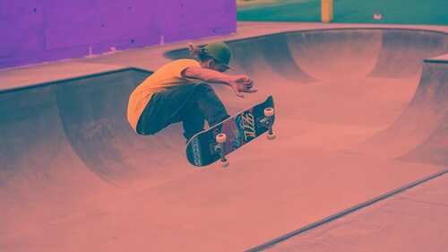 Skater realizando un kickflip en un skatepark moderno de hormigón con iluminación dramática